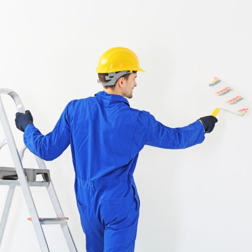Worker renewing apartment on wall background